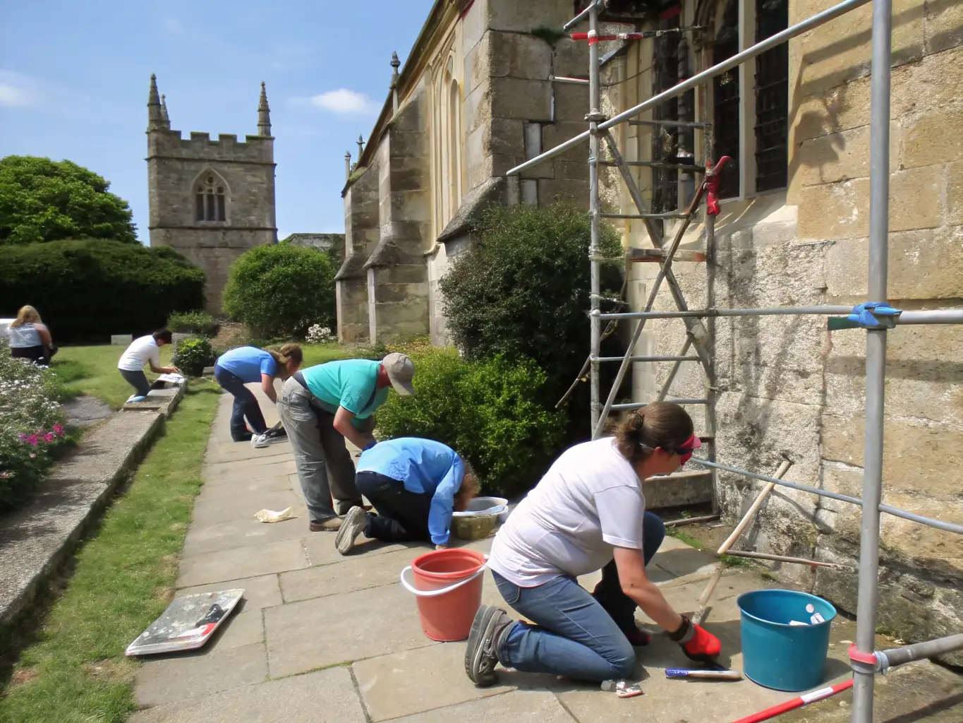 A group of volunteers working together to restore a section of the abbatiale's stonework, showcasing the hands-on preservation efforts of LES AMIS DE L'ABBATIALE.